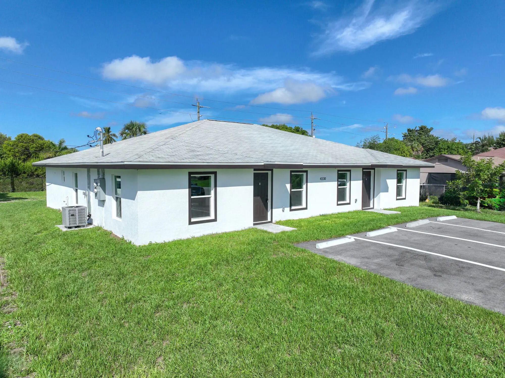 On Gulfstream Drive in Naples, FL, TN Capital Investments' white single-story building with gray roof sits by a small parking lot.