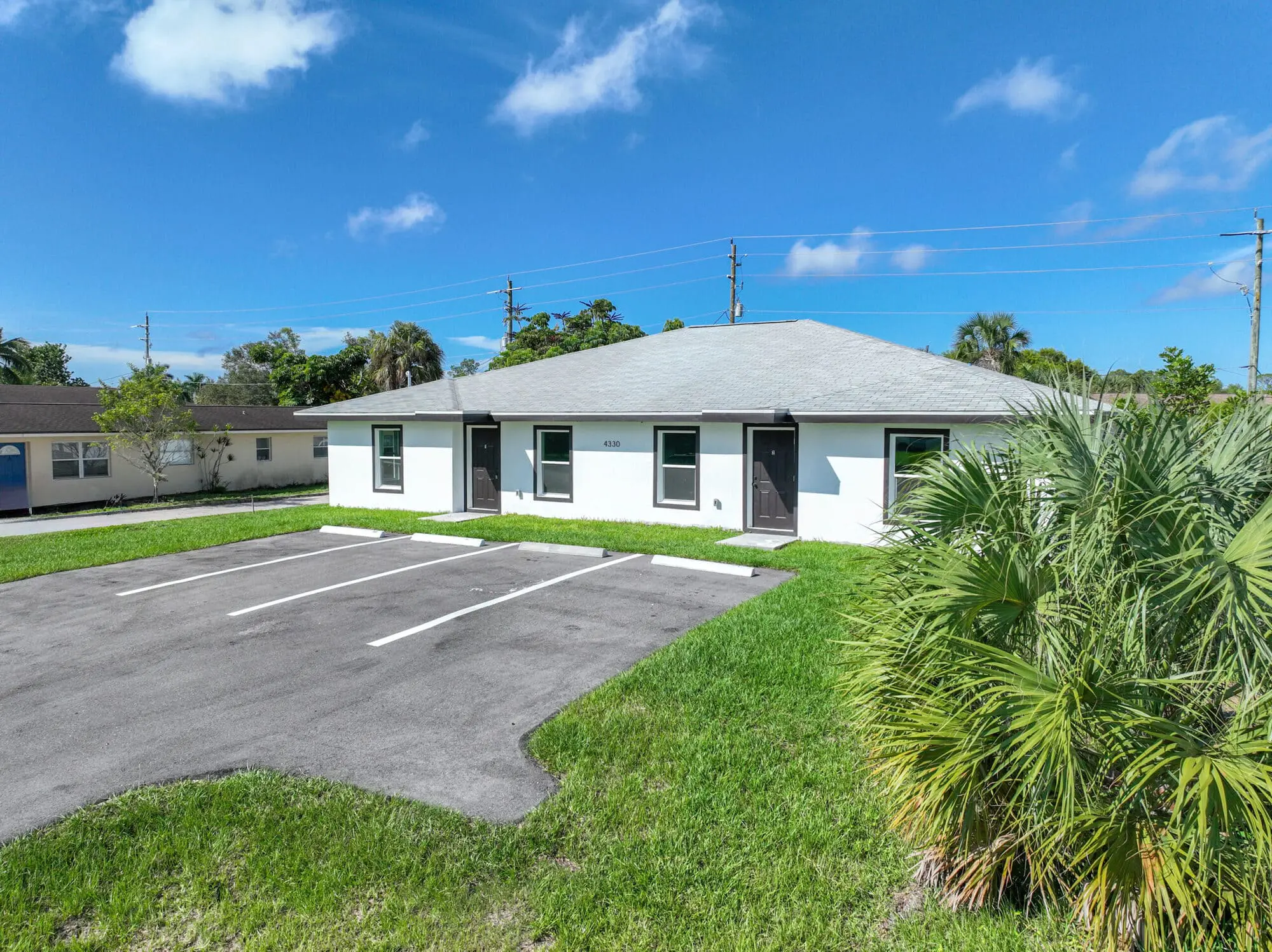 On Gulfstream Drive in Naples, FL, TN Capital Investments occupies a white single-story building amid grass, palms, and empty lot.