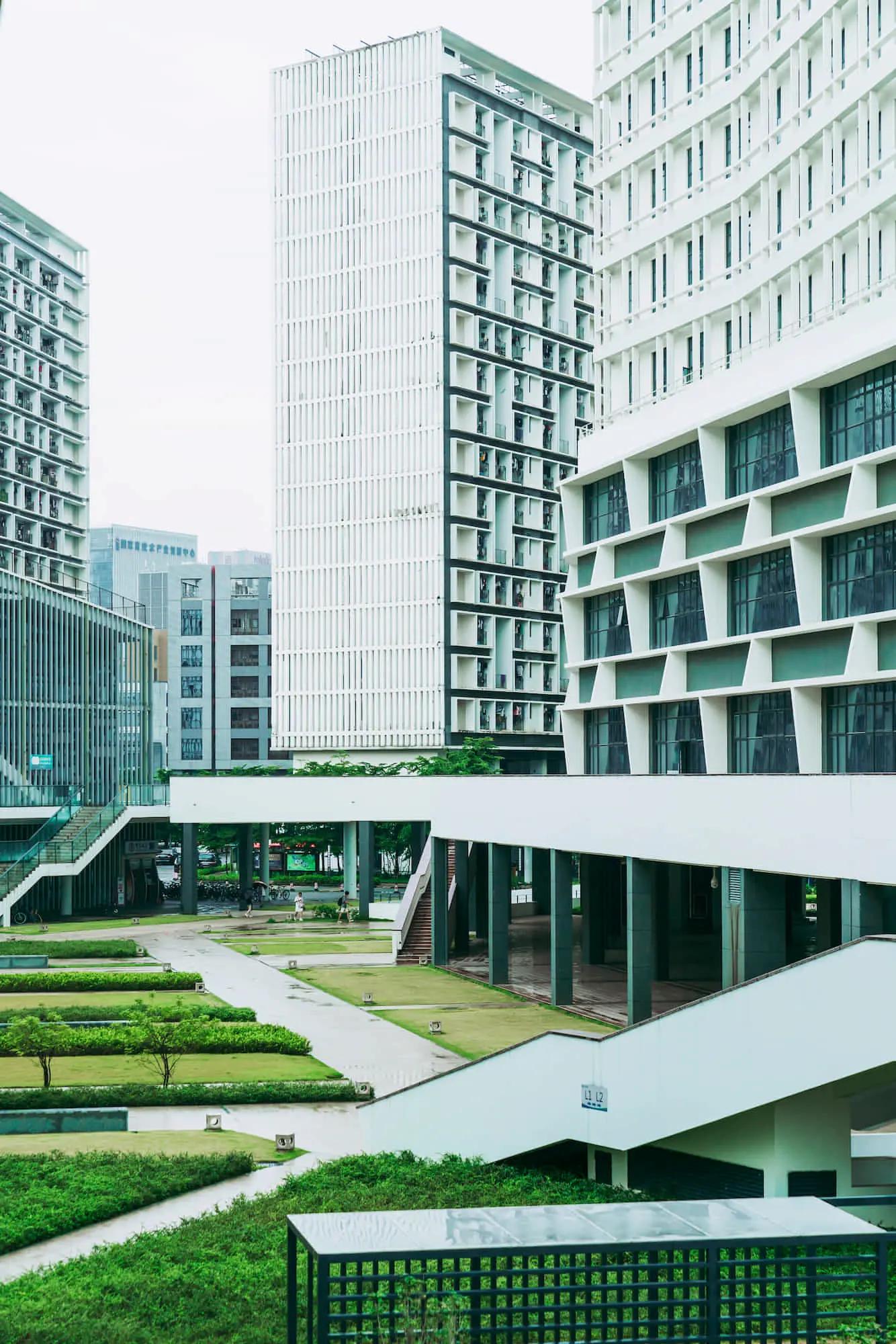 A landscaped courtyard with lawns and walkways is surrounded by TN Capital Investments’ modern buildings in Naples, FL.