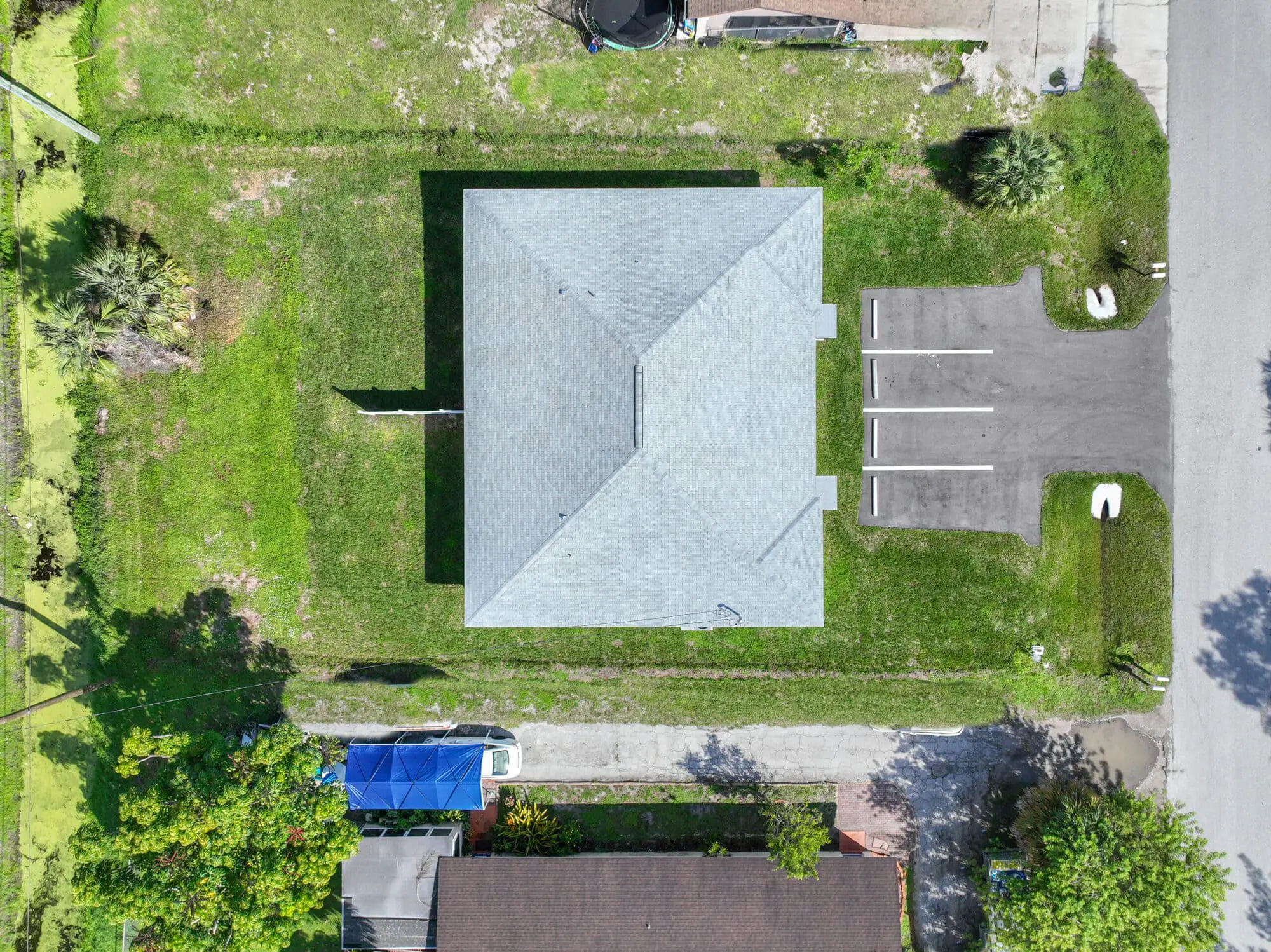 Aerial view of TN Capital Investments' single-story building with gray roof in Naples, FL, parking lot, and nearby white vehicle.