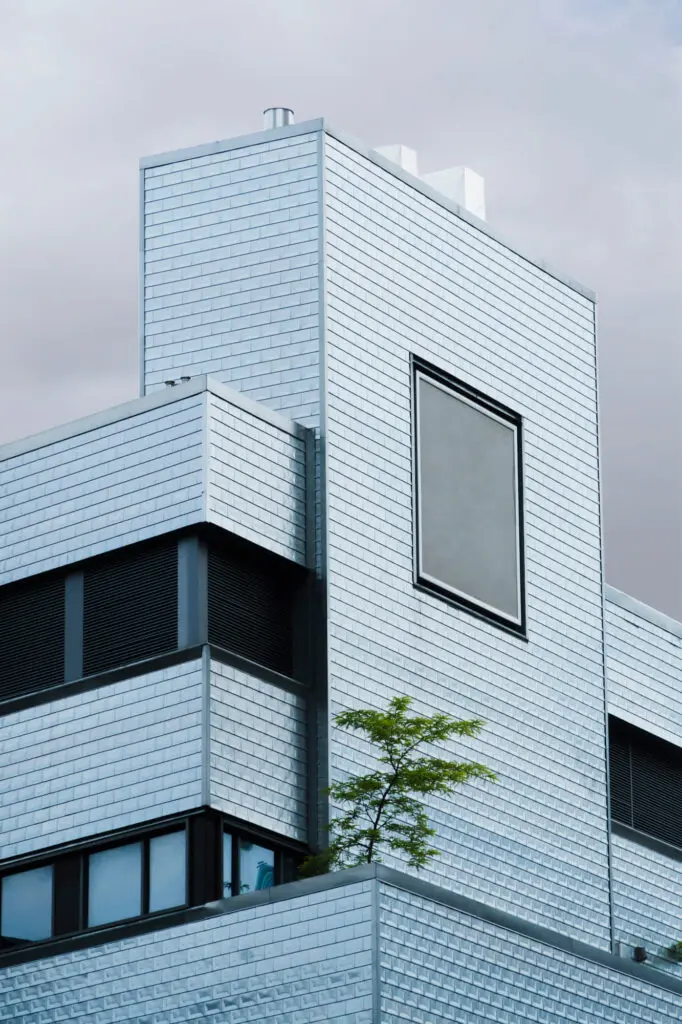 A sleek TN Capital Investments building in Naples, FL with metallic cladding, a big window, and balcony tree under cloudy skies.