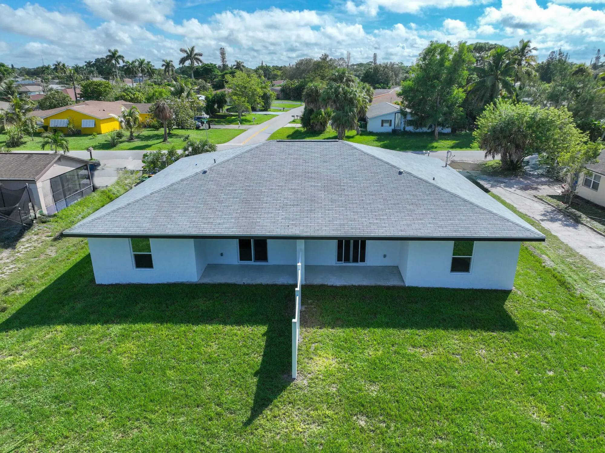 Aerial view of a white duplex with gray roof and sliding doors by TN Capital Investments on Gulfstream Drive in Naples, FL.