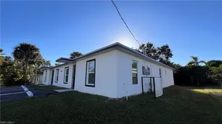 TN Capital Investments' white single-story building in Naples, FL sits on a grassy lot along Peters Avenue, with trees and parking nearby.