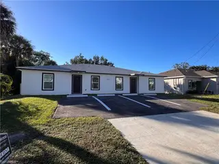 On Peters Avenue in Naples, FL, a duplex by TN Capital Investments features two front doors, lawn, and driveway under blue sky.