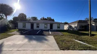 On Peters Avenue in Naples, FL, a TN Capital Investments duplex with three front doors, driveway, and parking under a sunny blue sky.