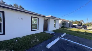 White house at 3120 Peters Ave in Naples, FL, with brown door, two windows, grassy lawn, and TN Capital Investments parking.