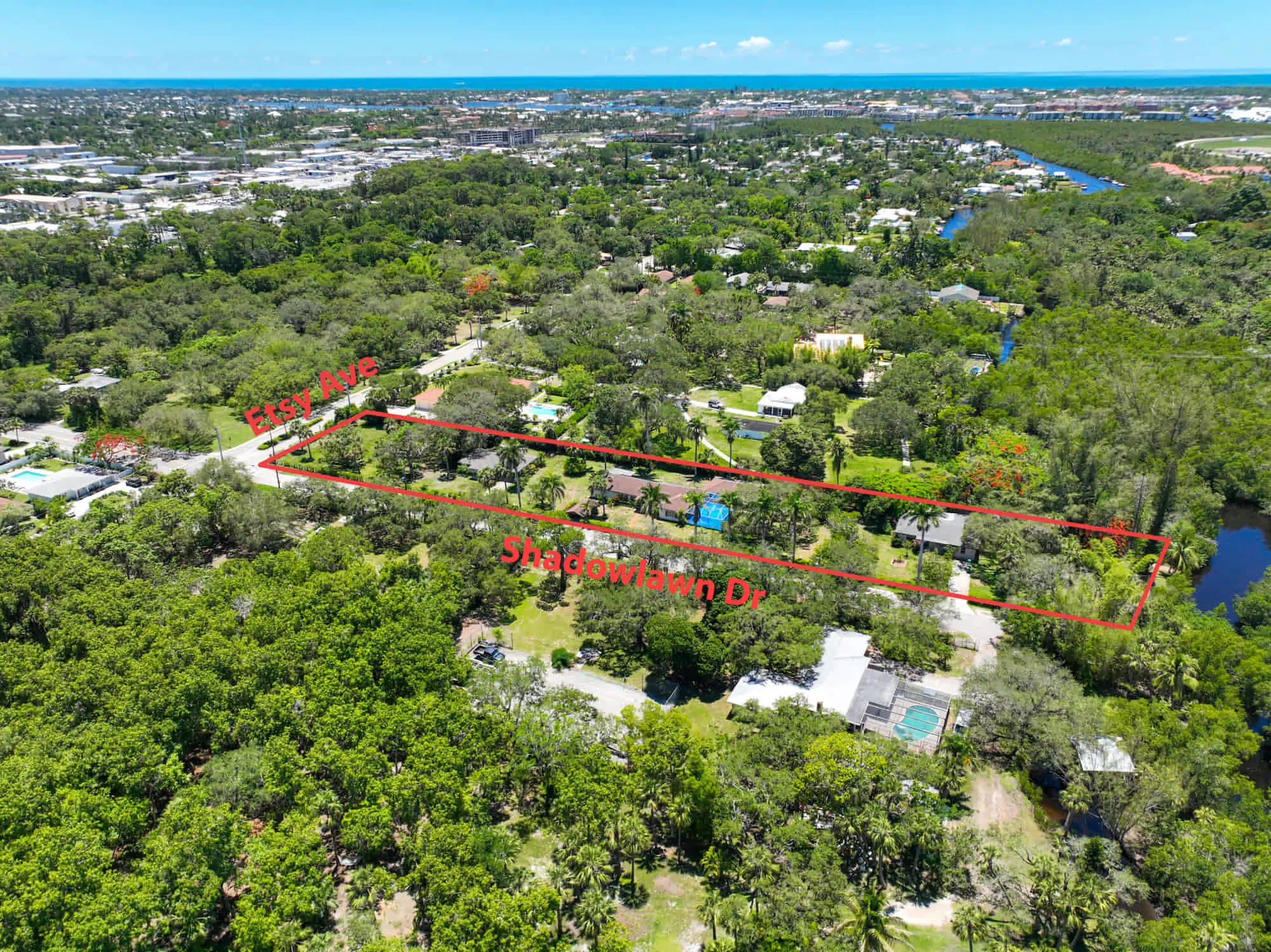 Rectangular plot outlined in red by TN Capital Investments in Naples, FL, between East Ave and Shadowlawn Drive; trees, houses nearby.
