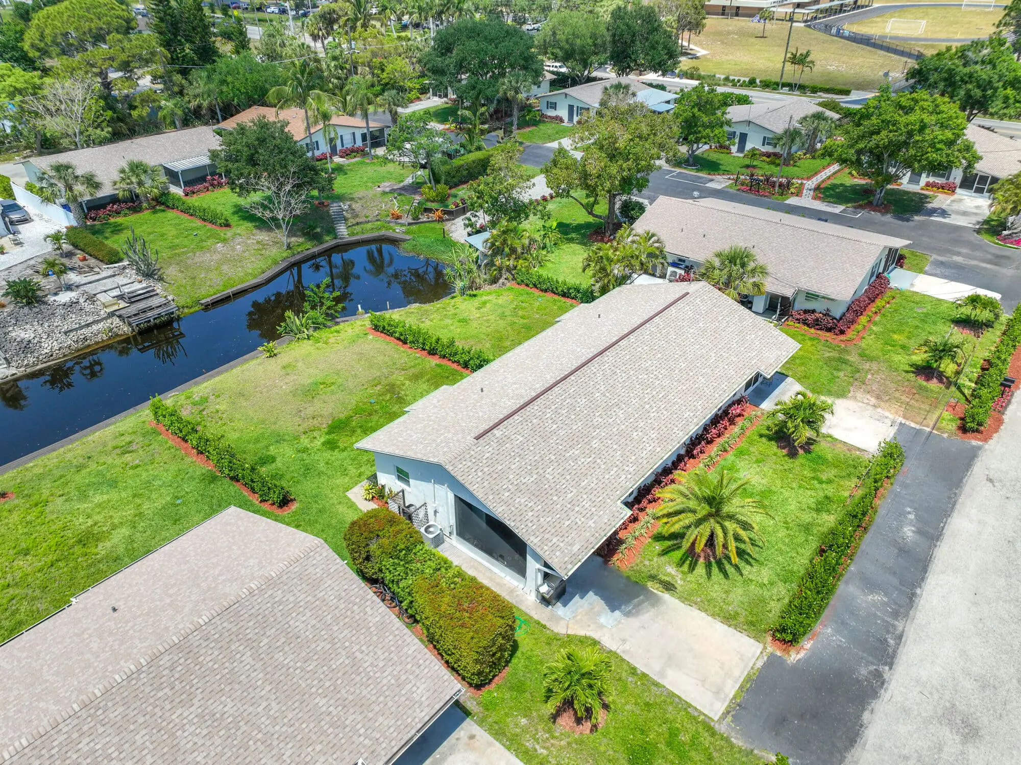 Suburban neighborhood in Naples, FL with single-story homes, green lawns, canal, and driveways, viewed for TN Capital Investments.
