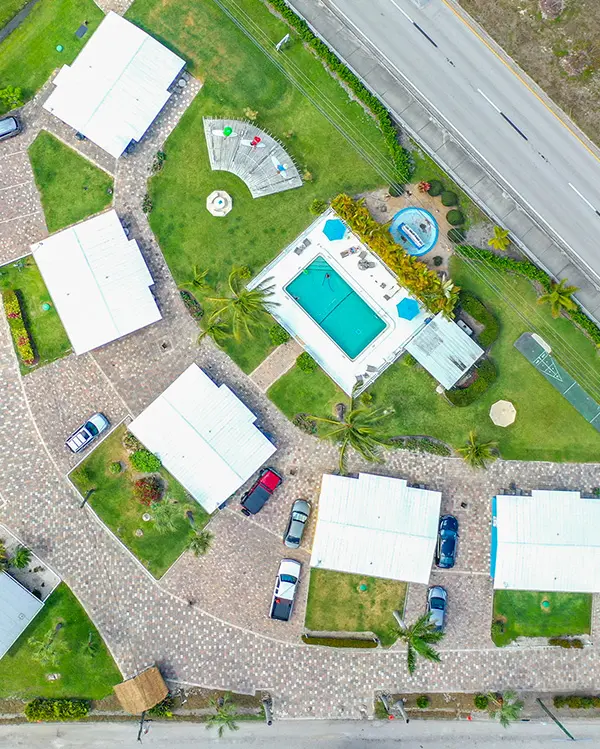 Aerial view of TN Capital Investments properties in Naples, FL: white-roofed houses, central pool, green lawns, cars, and roads.