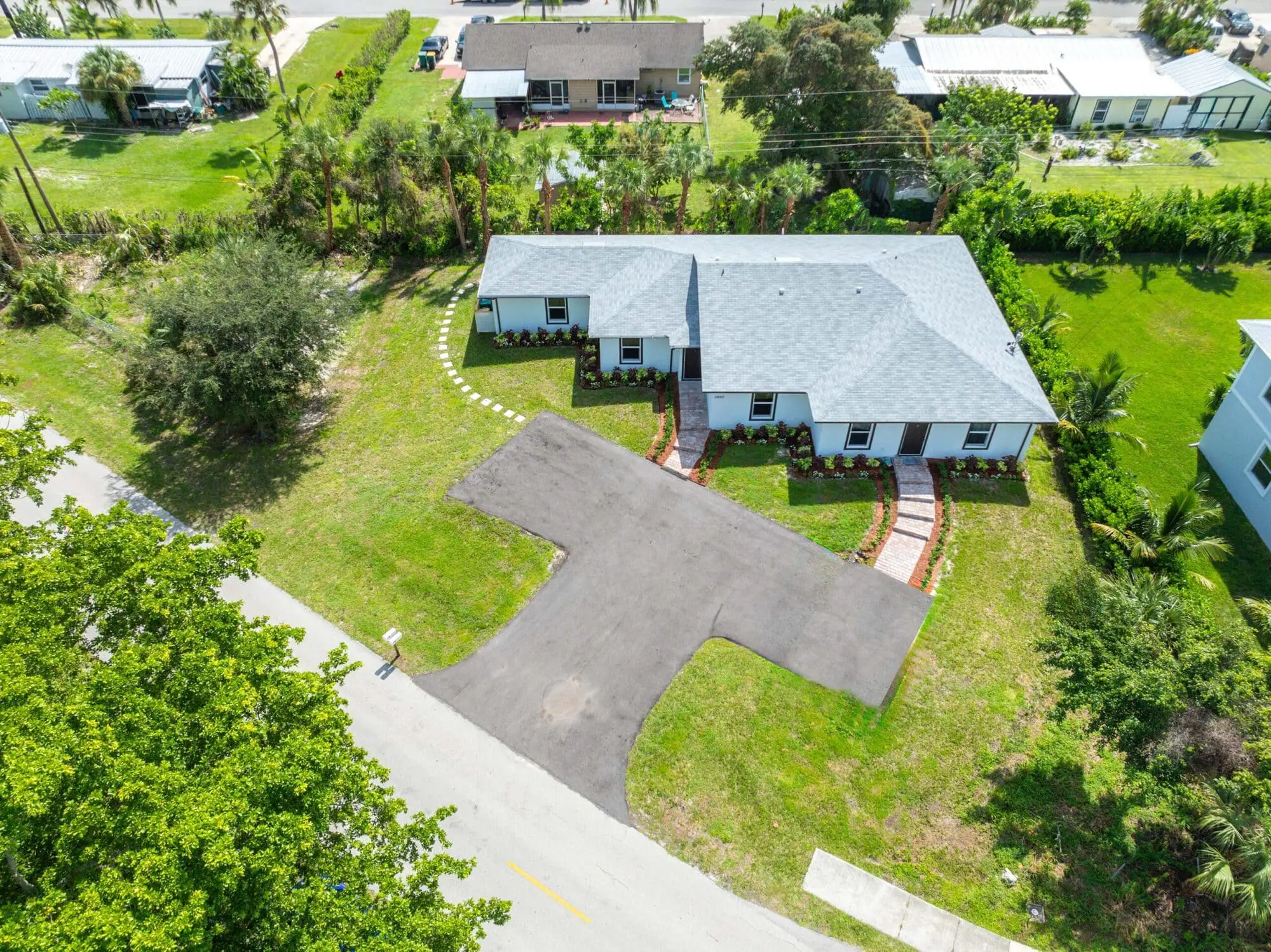 Aerial view of a suburban single-story house with gray roof and landscaped yard, owned by TN Capital Investments in Naples, FL.
